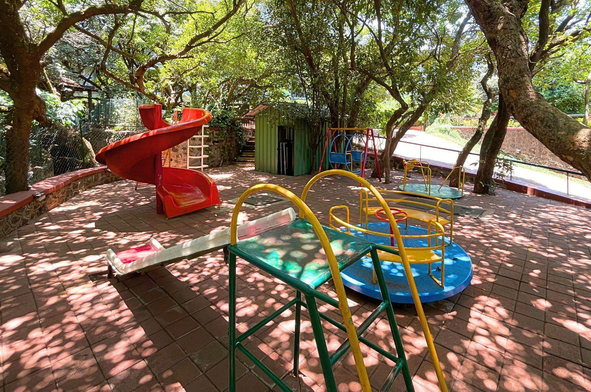 A well-shaded outdoor fitness zone at Ramsukh Resort, set amidst greenery, featuring exercise machines for physical activity in a natural setting.